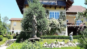 A two-story house with a balcony, surrounded by a well-maintained garden with a statue. - Ferienwohnung Nr. 1 - "Panoramablick", 108 qm Obergeschoss, 1 separates Schlafzimmer (Bad Endorf)