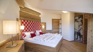 Ein Schlafzimmer mit hölzernem Kopfteil, einem Bett mit weißen Bettwäsche, einem Nachttisch mit Lampe und einem an der Wand befestigten Regal.