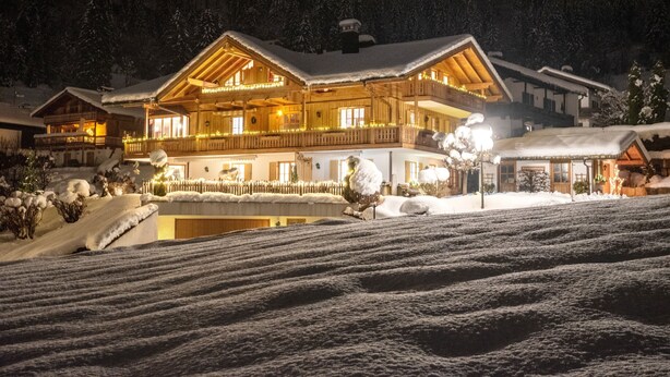 Ein großes, mehrstöckiges Holzhotel mit Balkonen und einer überdachten Außenbereich, umgeben von verschneiter Landschaft.