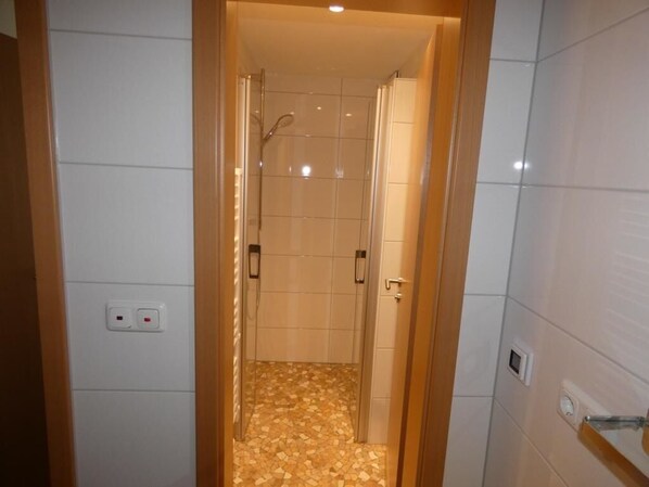 Un pasillo estrecho que conduce a un área de ducha con paredes y piso de baldosas.