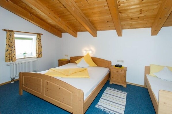 A bedroom with a wooden bed, a nightstand, a dresser, and a window with curtains.