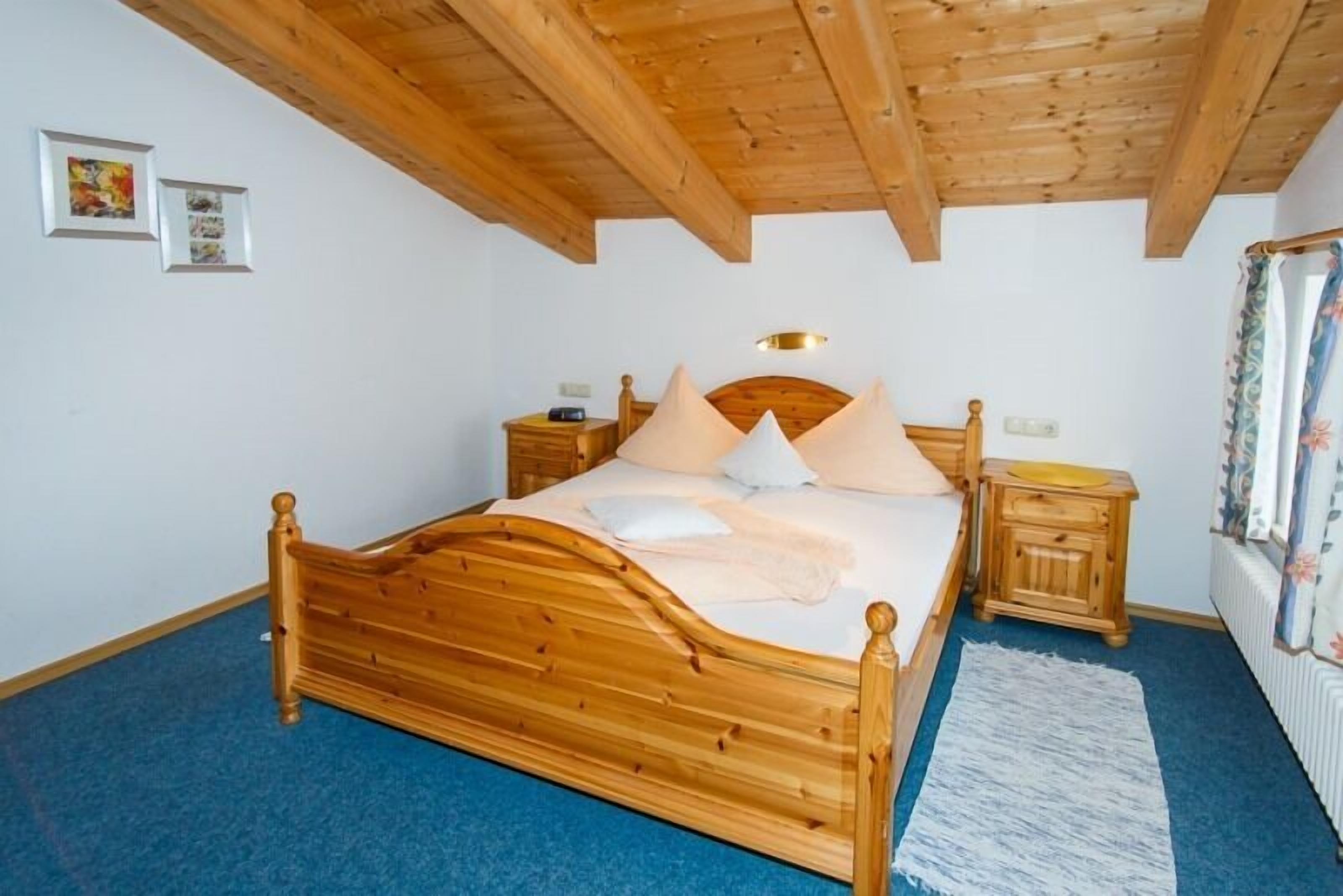 A wooden bed with a headboard, two bedside tables, and a blue carpet.