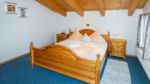 Una cama de madera con cabecera, dos mesitas de noche y una alfombra azul.