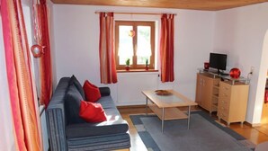 En hyggelig stue med en sofa, et lille bord og et fjernsyn på et skab.