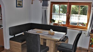 Et hyggeligt spiseområde med et træbord, sorte polstrede stole og en bænk.