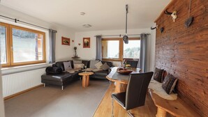 A modern living room with a sofa, coffee table, and dining area. - Vacation apartment Bergfeuer, for 1-4 persons (Berchtesgaden)