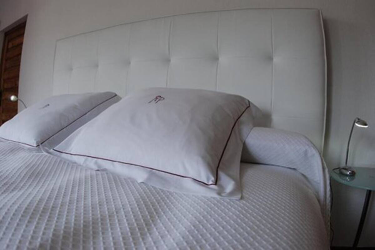 Una cama bien hecha con un cabecero capitonado y dos almohadas.