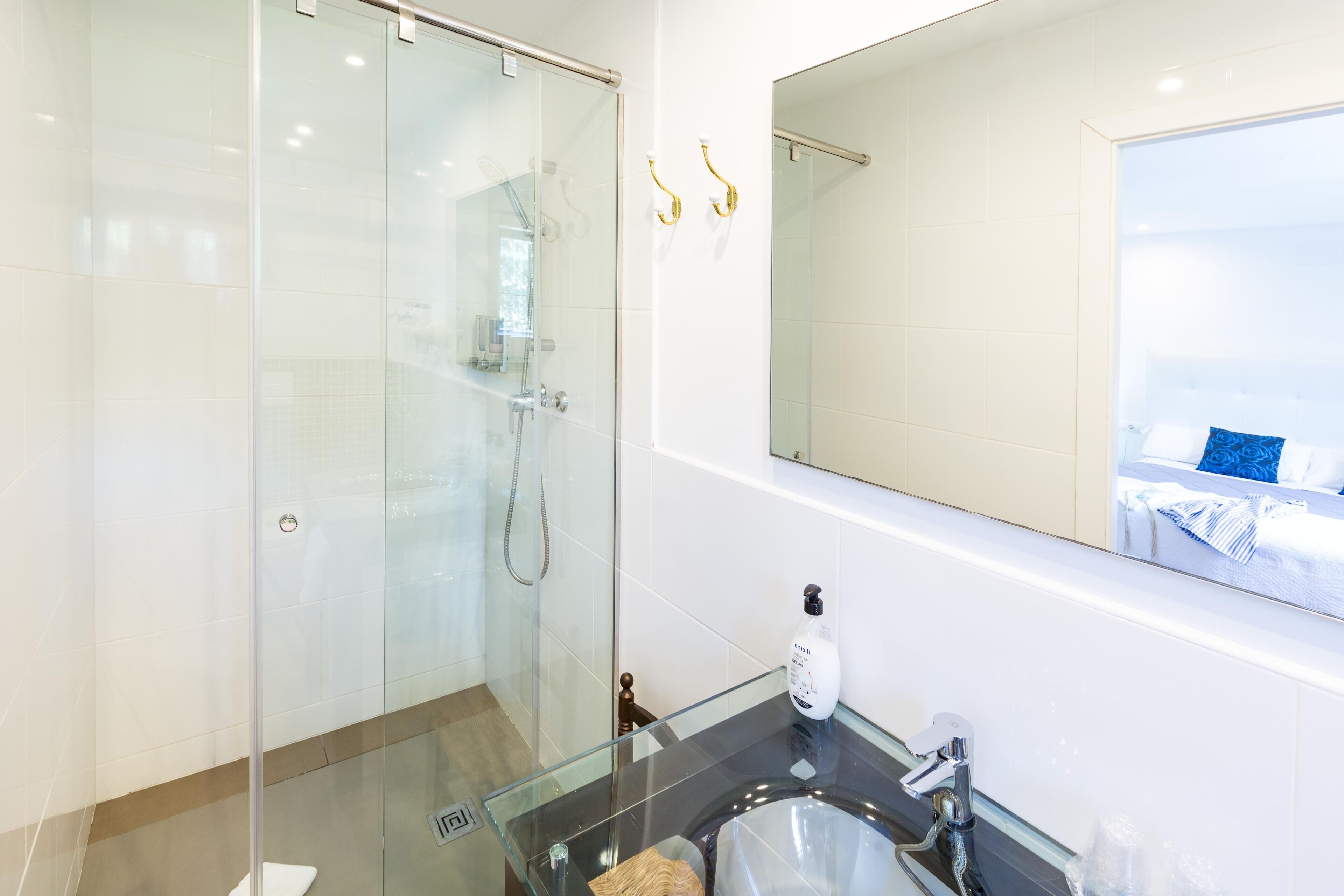 A modern bathroom with a glass shower enclosure, a glass sink, and a large mirror.