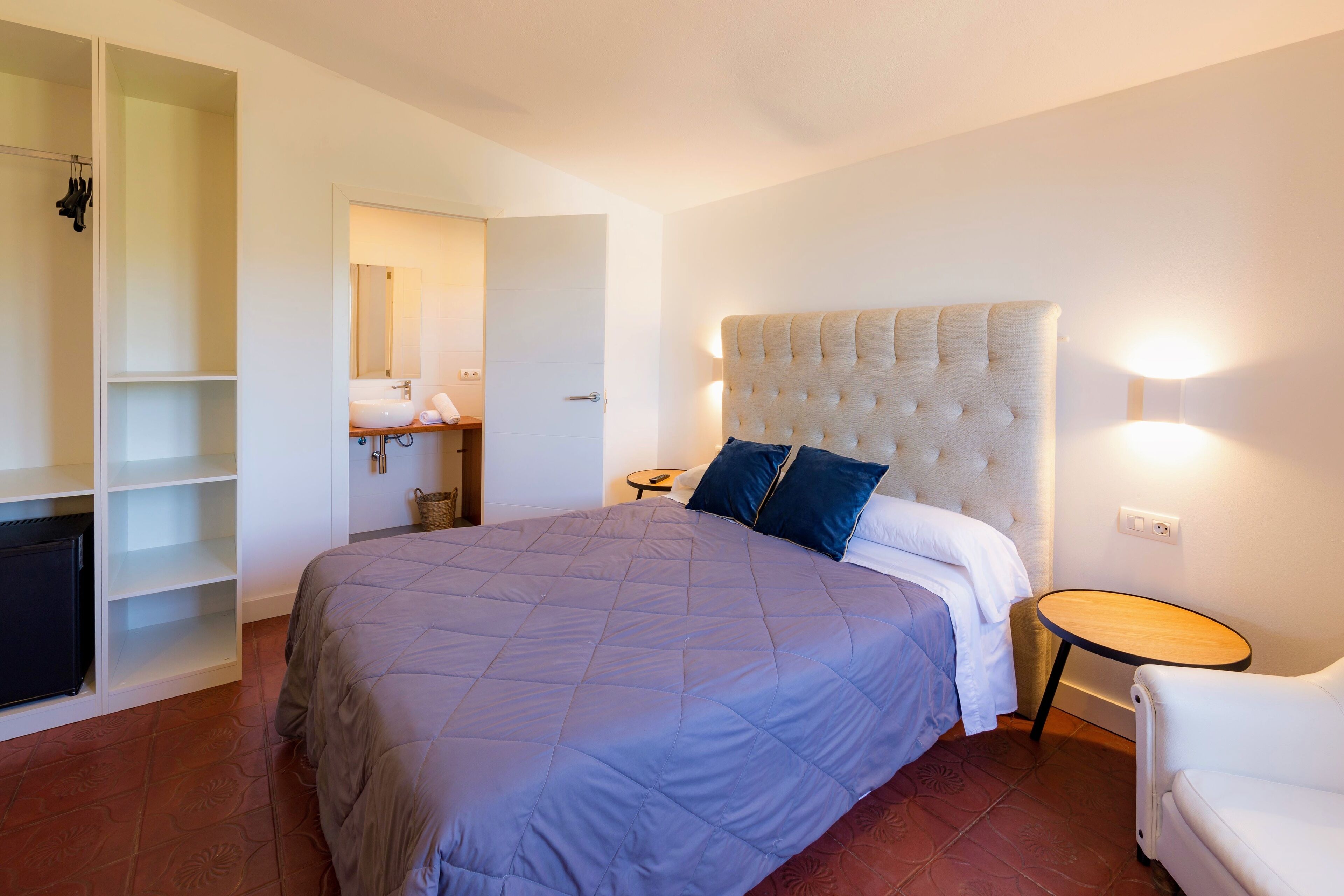A bedroom with a large bed, a wardrobe, a bedside table, and a chair.