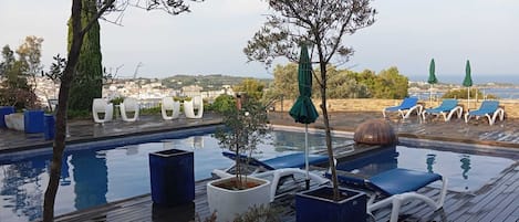 Una piscina al aire libre, sillones reclinables de piscina