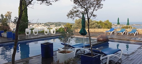 Una piscina al aire libre, sillones reclinables de piscina
