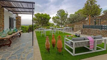 An outdoor patio with stone flooring, a white sofa, terracotta pots, and a pergola.
