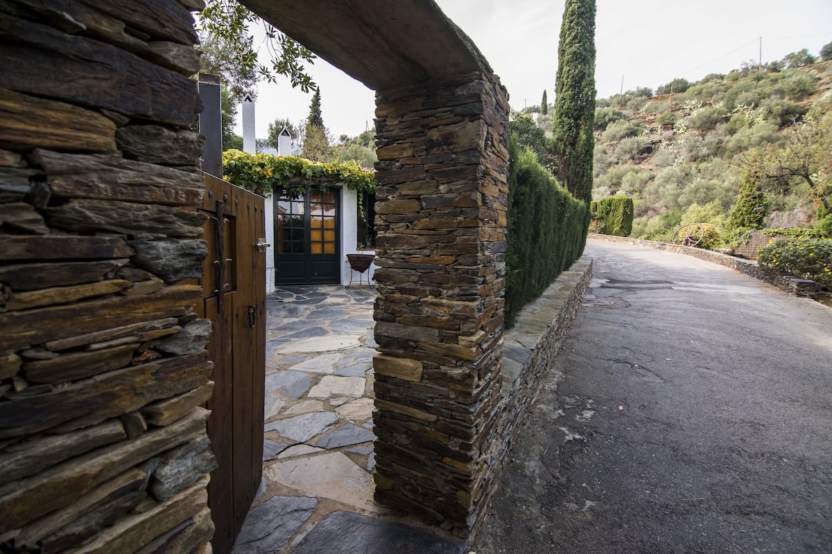 Un arco de piedra que da acceso a un edificio de piedra con una puerta y una ventana.