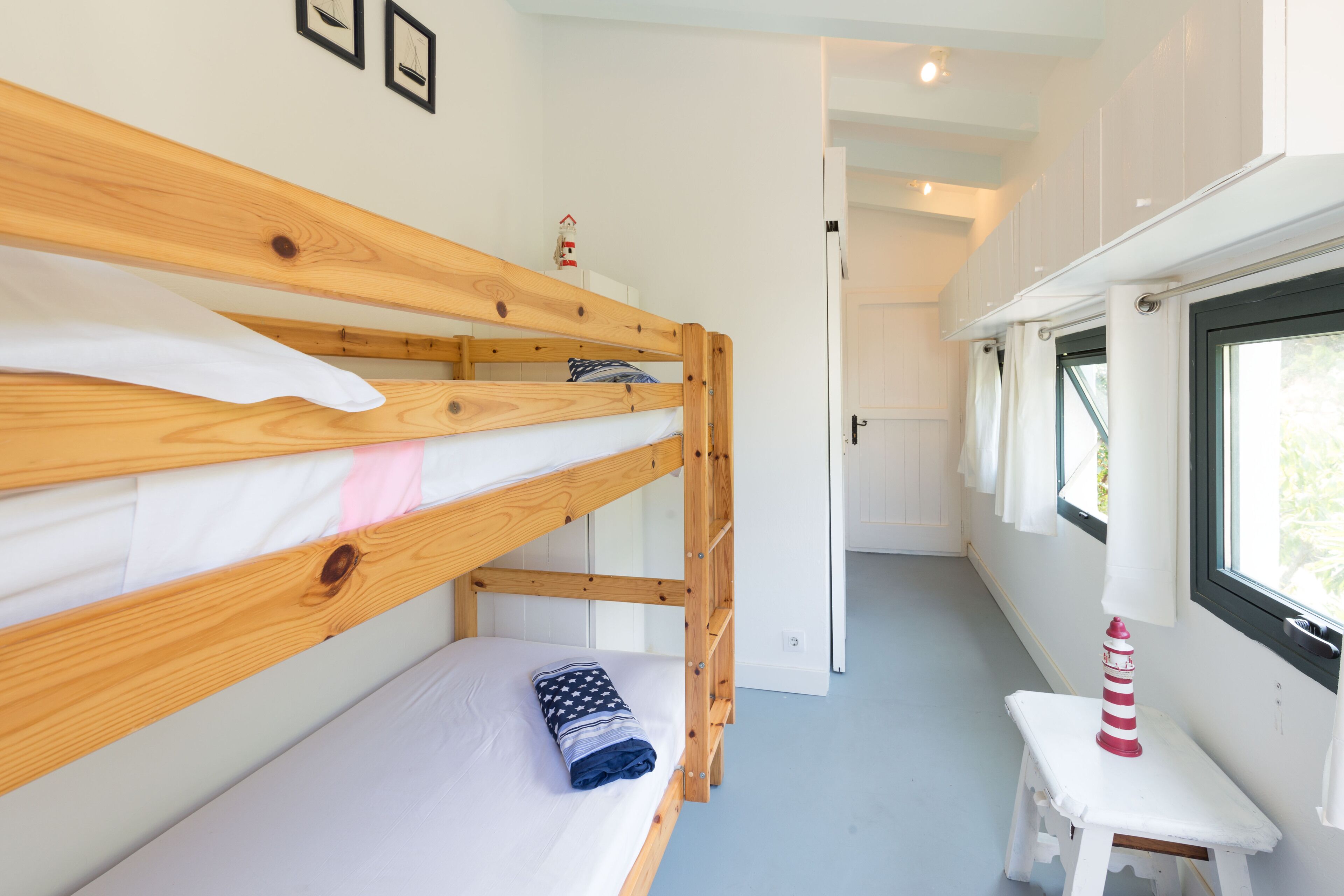 A bunk bed with a small table and a window with curtains.