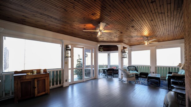 A spacious balcony with wooden flooring, a ceiling fan, and a view of the city. - Brinckerhoff Inn (Fishkill)