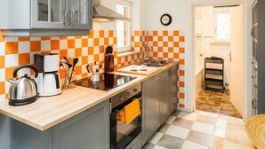 Een kleine keuken met een geruit spatwand, een koffiezetapparaat, een waterkoker en een broodrooster.