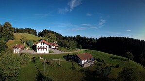 Ein großes Haus mit rotem Dach auf einem Hügel, umgeben von Bäumen.