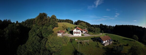 A large house with a red roof on a hill surrounded by trees.