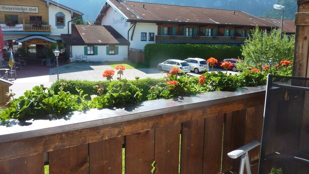 Un hôtel situé au pied d’une montagne, avec une cour intérieure agrémentée de voitures et de fleurs.