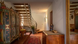 A staircase with a decorative railing, a wooden cabinet with floral patterns, and a red patterned rug. - Vacation apartment no. 1 Watzmann, 70sqm for 2 persons (Berchtesgaden)