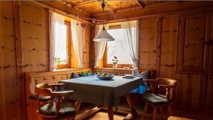 A cozy wooden dining room with a table and chairs, a hanging light fixture, and a window with curtains. - Vacation apartment no. 1 Watzmann, 70sqm for 2 persons (Berchtesgaden)