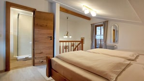A bedroom with a wooden door, a bed with white bedding, a hanging light fixture, and a window with curtains. - holiday flat (Ramsau bei Berchtesgaden)