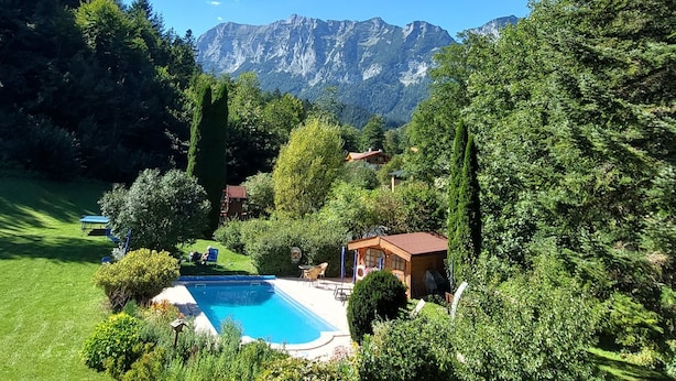 A backyard with a swimming pool, surrounded by lush greenery and a mountain view. - holiday flat (Ramsau bei Berchtesgaden)