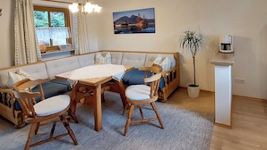 A cozy dining area with a wooden table, cushioned seating, a potted plant, and a coffee machine. - holiday flat (Ramsau bei Berchtesgaden)