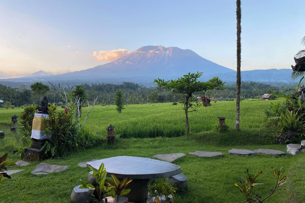 A serene landscape with a mountain in the background, a grassy area with a stone table, and scattered rocks.