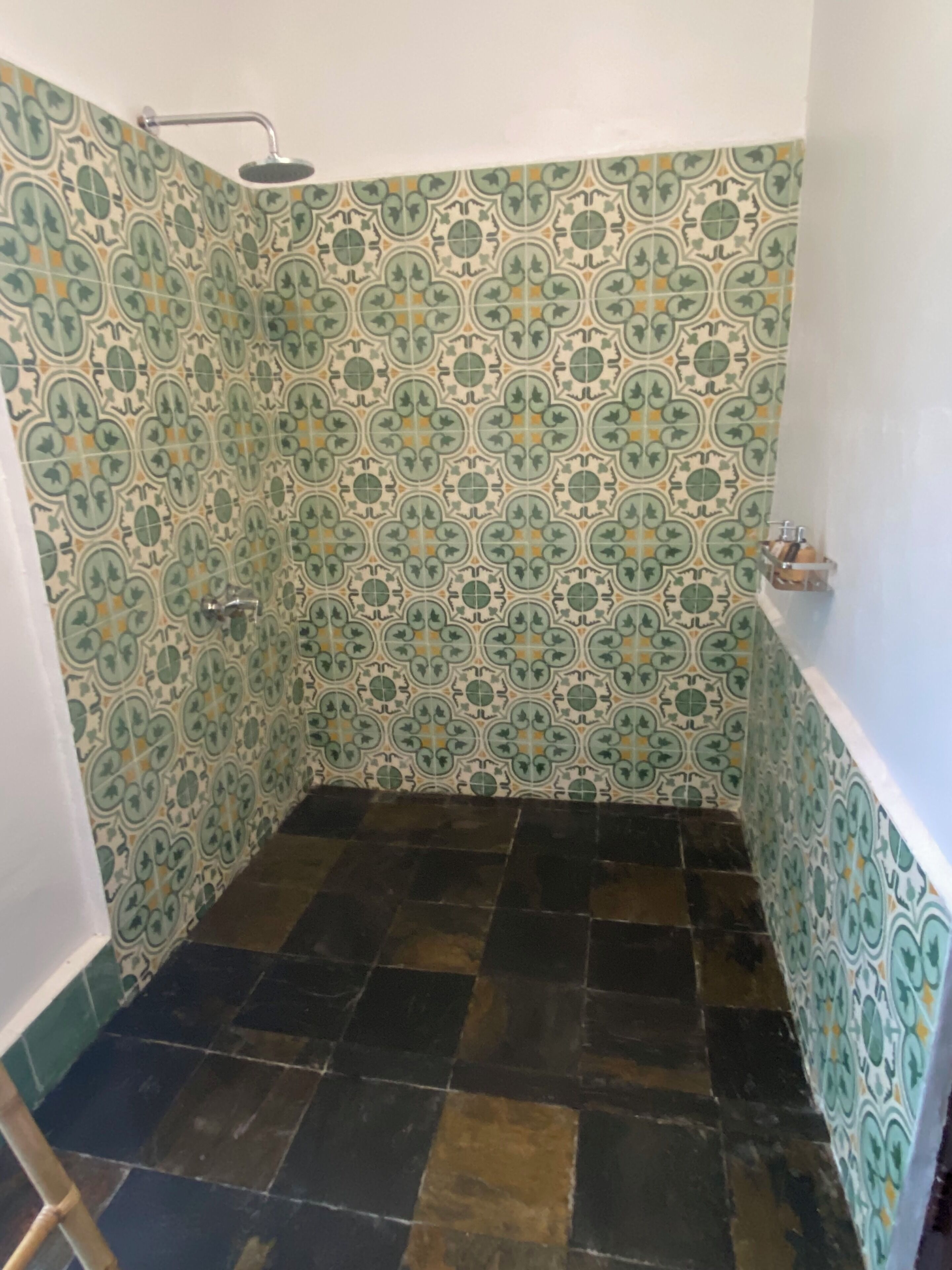 Un baño con azulejos estampados, una ducha y suelo de azulejos.
