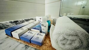 A bathroom with a marble countertop, a white towel, and various toiletries including body wash, soap, and lotion. - Hotel Aquetzalli (Yautepec)