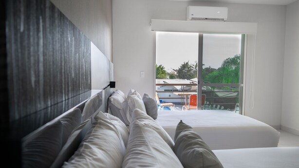 A modern hotel room with a large bed, a view of the outdoors, and a sliding glass door. - Hotel Aquetzalli (Yautepec)