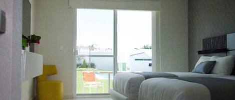 A bedroom with a bed, a small yellow chair, and a view through a sliding door.