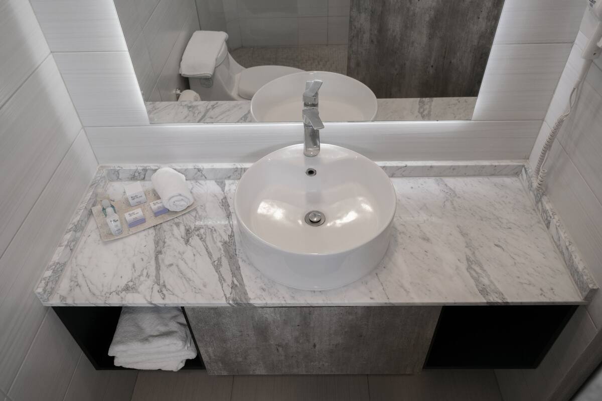 A bathroom with a marble sink, a towel rack, and a mirror.
