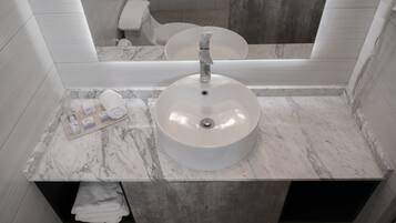 Un baño con lavamanos de mármol, toallero y espejo.