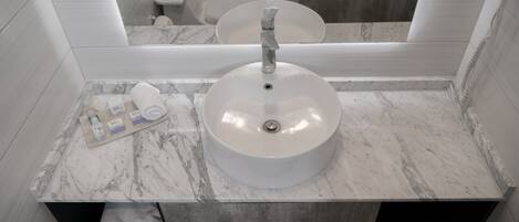 Un baño con lavamanos de mármol, toallero y espejo.