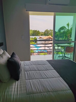 A hotel room with a bed, a view of a pool and outdoor seating area. - Hotel Aquetzalli (Yautepec)