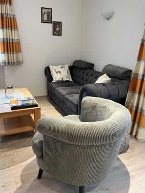 A living room with a grey sofa, a wooden coffee table, and a grey armchair.