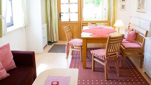 Ett mysigt rum med ett matbord i trä, stolar, en soffa och ett fönster med gardiner.