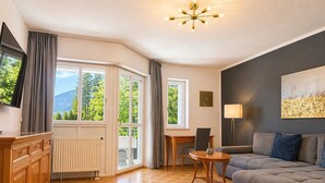 A modern living room with a sofa, a dining table, and a TV. - Apartment no. 16, 62sqm, bathroom with bathtub, living/bedroom, balcony (Bad Reichenhall)
