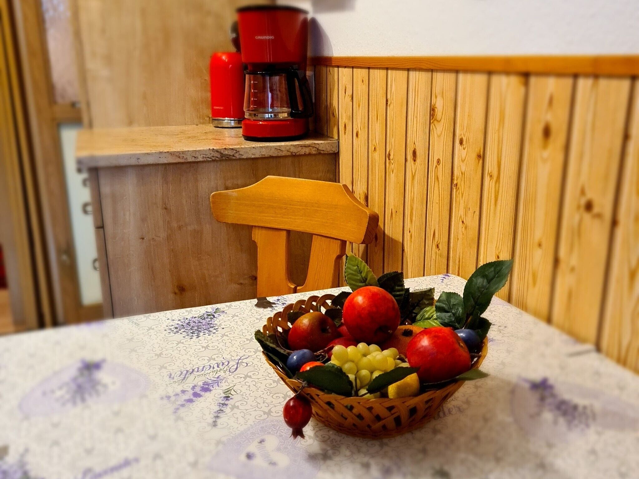 Una silla de madera y una mesa con una cesta de frutas.