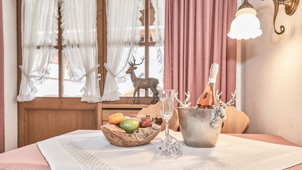 A dining table with a white tablecloth, a wooden bowl with fruits, a glass, and a metal container with utensils. - (8) Zwei-Raum-Ferienwohnung 38qm, Bad/WC, Extra-Schlafraum, Küche, Balkon (Reit im Winkl)