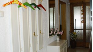 A hallway with white walls, wooden ceiling, and a white dresser with a mirror and vase of flowers. - Apartment 38sqm, balcony, kitchenette, 1 bedroom, WLAN, no pets (Ruhpolding)