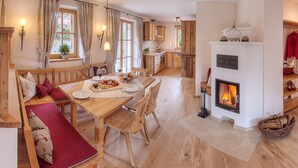 Un comedor acogedor con muebles de madera, una chimenea y una cocina al fondo.