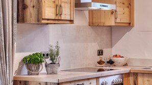Una cocina con armarios de madera, una campana extractora de acero inoxidable, un fregadero y una encimera con una cesta de hierbas y una planta en maceta.