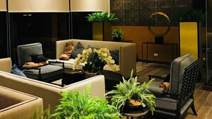 A modern living room with a large chandelier, comfortable seating, and decorative plants. - Astra Suites Central (Chiang Mai)