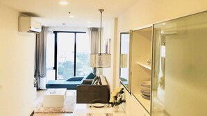 A modern hotel room with a dining area, a large window with a view, and a flat-screen TV mounted on the wall. - Astra Suites Central (Chiang Mai)
