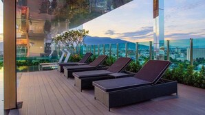 A rooftop lounge with sun loungers and a city view. - Astra Suites Central (Chiang Mai)
