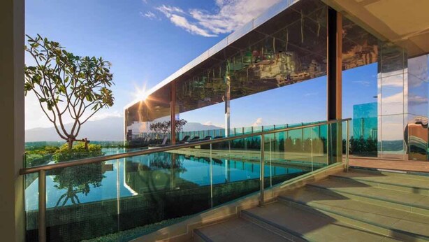 A modern building with a glass balcony overlooking a pool and a clear sky. - Astra Suites Central (Chiang Mai)