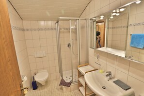 Un baño con ducha, inodoro, lavamanos y espejo.